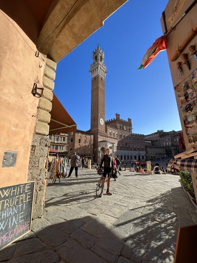 A cyclist poses in Siena's famous Piazza del Campo